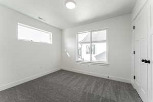 Empty room with a textured ceiling and dark carpet