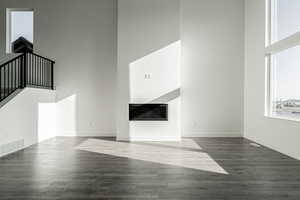 Unfurnished living room featuring dark hardwood / wood-style flooring and a towering ceiling