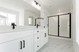 Bathroom with vanity, a shower with door, and plenty of natural light