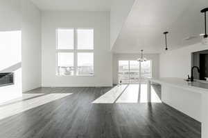 Unfurnished living room featuring dark hardwood / wood-style flooring, sink, a textured ceiling, and a notable chandelier