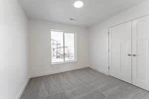 Unfurnished bedroom featuring light carpet and a closet