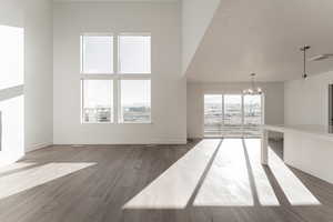 Unfurnished living room with hardwood / wood-style floors, a textured ceiling, and an inviting chandelier