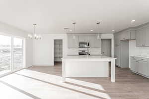 Kitchen featuring appliances with stainless steel finishes, light hardwood / wood-style flooring, and an island with sink