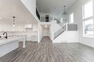 Kitchen featuring decorative light fixtures, an inviting chandelier, white cabinetry, and light hardwood / wood-style flooring