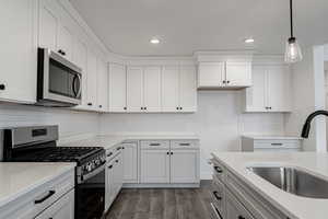 Kitchen featuring pendant lighting, white cabinetry, sink, and appliances with stainless steel finishes