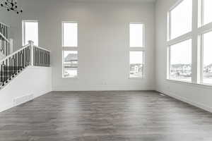 Unfurnished living room featuring a towering ceiling and dark hardwood / wood-style floors