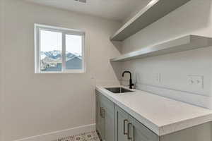 Kitchen featuring sink, light stone countertops, gray cabinets, and light tile patterned floors