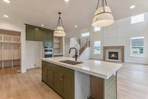 Kitchen featuring a kitchen island with sink, light hardwood / wood-style flooring, a brick fireplace, and sink