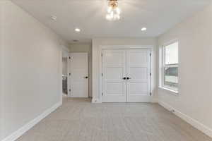 Unfurnished bedroom featuring light carpet and a closet