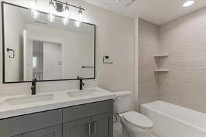 Full bathroom featuring tiled shower / bath combo, double sink vanity, and toilet