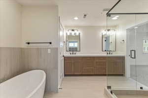 Bathroom featuring shower with separate bathtub, tile patterned floors, tile walls, and double vanity