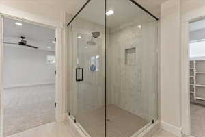 Bathroom with ceiling fan, an enclosed shower, and tile patterned flooring