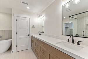 Bathroom with dual vanity, tile patterned floors, plus walk in shower, and a textured ceiling