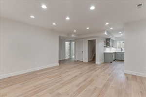 Unfurnished living room with sink and light wood-type flooring