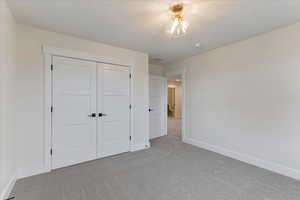 Unfurnished bedroom with light carpet and a closet