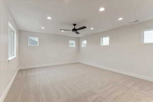 Carpeted spare room with a healthy amount of sunlight and ceiling fan