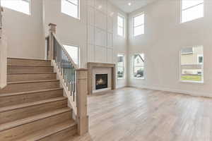 Unfurnished living room with a fireplace, light wood-type flooring, and a high ceiling