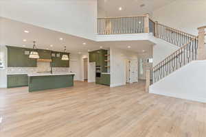 Unfurnished living room with light hardwood / wood-style flooring and a towering ceiling