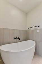 Bathroom featuring tile patterned flooring, tile walls, and a tub to relax in