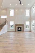 Unfurnished living room featuring light hardwood / wood-style flooring, ceiling fan, and a towering ceiling