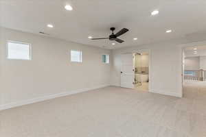 Unfurnished bedroom with connected bathroom, light colored carpet, and ceiling fan