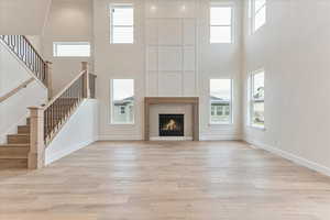 Unfurnished living room featuring a high ceiling, a fireplace, and light hardwood / wood-style floors