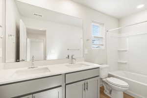 Full bathroom with washtub / shower combination, vanity, toilet, and hardwood / wood-style flooring