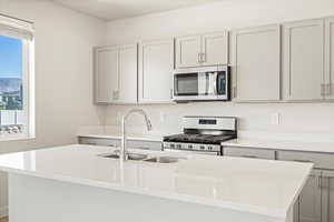 Kitchen featuring an island with sink, stainless steel appliances, and sink