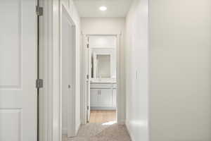 Hallway featuring light colored carpet and sink