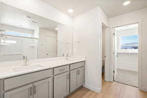 Bathroom with toilet, vanity, hardwood / wood-style floors, and an enclosed shower