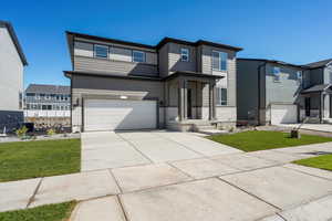 View of front of home featuring central AC unit, a garage, and a front yard