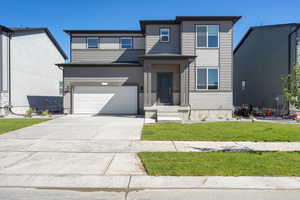 View of front facade featuring a front yard and a garage