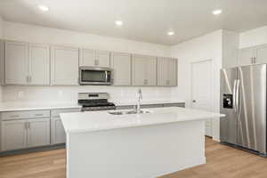 Kitchen featuring a kitchen island with sink, stainless steel appliances, sink, and light hardwood / wood-style floors