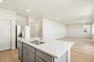 Kitchen featuring gray cabinets, a kitchen island with sink, sink, light hardwood / wood-style flooring, and stainless steel dishwasher