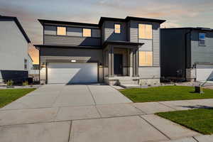 View of front facade featuring a garage and a yard