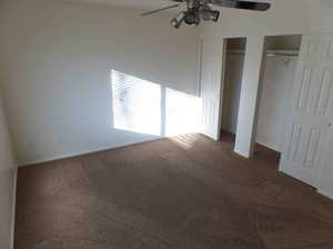 Unfurnished bedroom featuring multiple closets, carpet floors, and ceiling fan