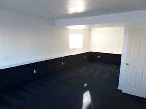 Spare room featuring dark colored carpet and a textured ceiling