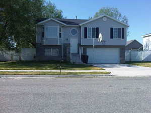 Raised ranch featuring a garage and a front lawn