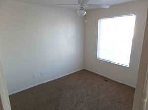 Carpeted empty room with ceiling fan and a wealth of natural light