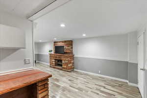 Living room with a stone fireplace and light wood-type flooring