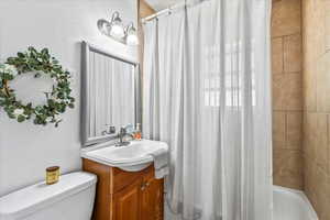 Full bathroom featuring shower / bathtub combination with curtain, toilet, and vanity