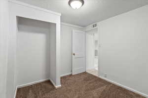 Unfurnished bedroom featuring light colored carpet and a textured ceiling