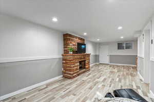 Unfurnished living room featuring a stone fireplace and light hardwood / wood-style floors