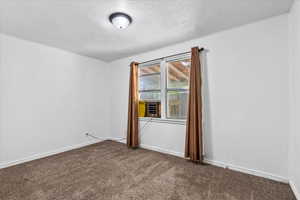 Carpeted front bedroom featuring a textured ceiling