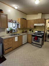 Kitchen featuring range with gas stovetop, sink, dishwasher, washer / clothes dryer, and light tile patterned floors