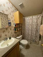 Bathroom featuring vanity, toilet, a textured ceiling, and tile patterned flooring