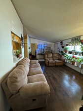 Living room featuring a textured ceiling, wood-type flooring, and lofted ceiling