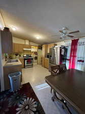 Kitchen featuring stove, stainless steel fridge, washer / dryer, a textured ceiling, and light tile patterned flooring