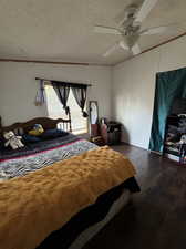 Bedroom featuring ceiling fan, hardwood / wood-style flooring, crown molding, and a textured ceiling