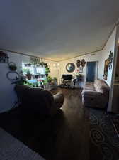 Living room with hardwood / wood-style flooring, a notable chandelier, and a textured ceiling